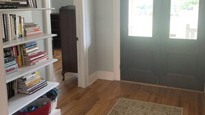 Een kamer met een boekenkast, een vloerkleed en een deur met gebogen ramen.