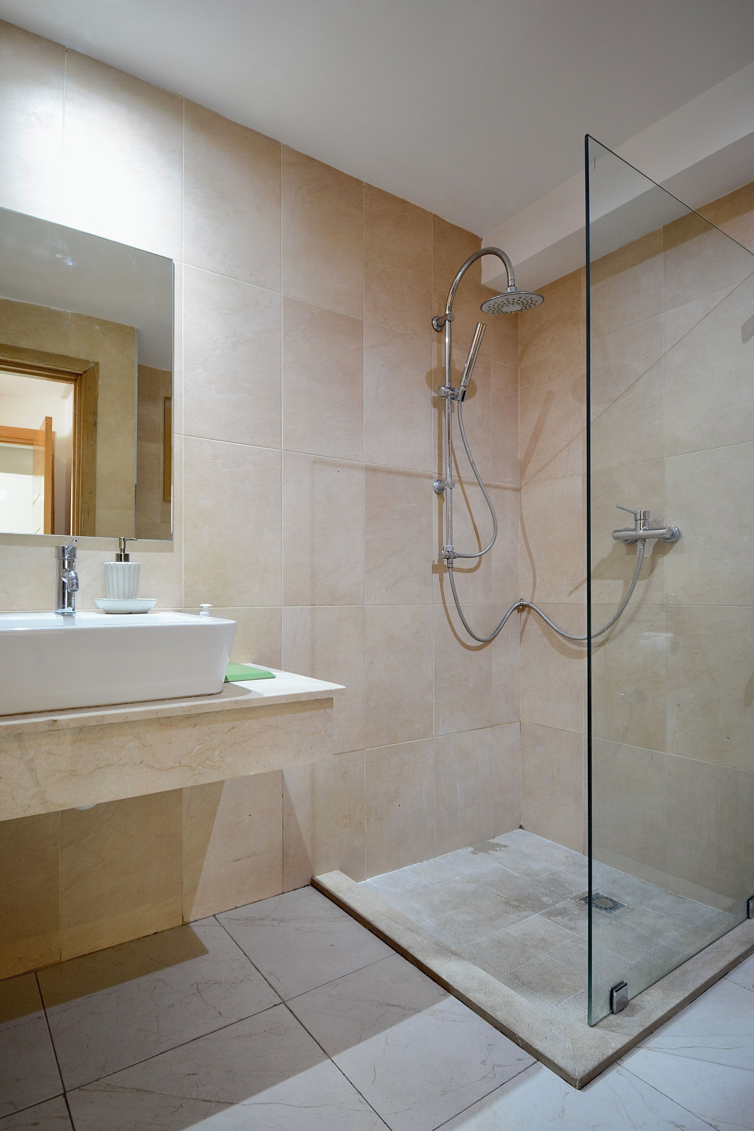 Une salle de bain moderne avec une douche à parois de verre, un lavabo blanc et un grand miroir.