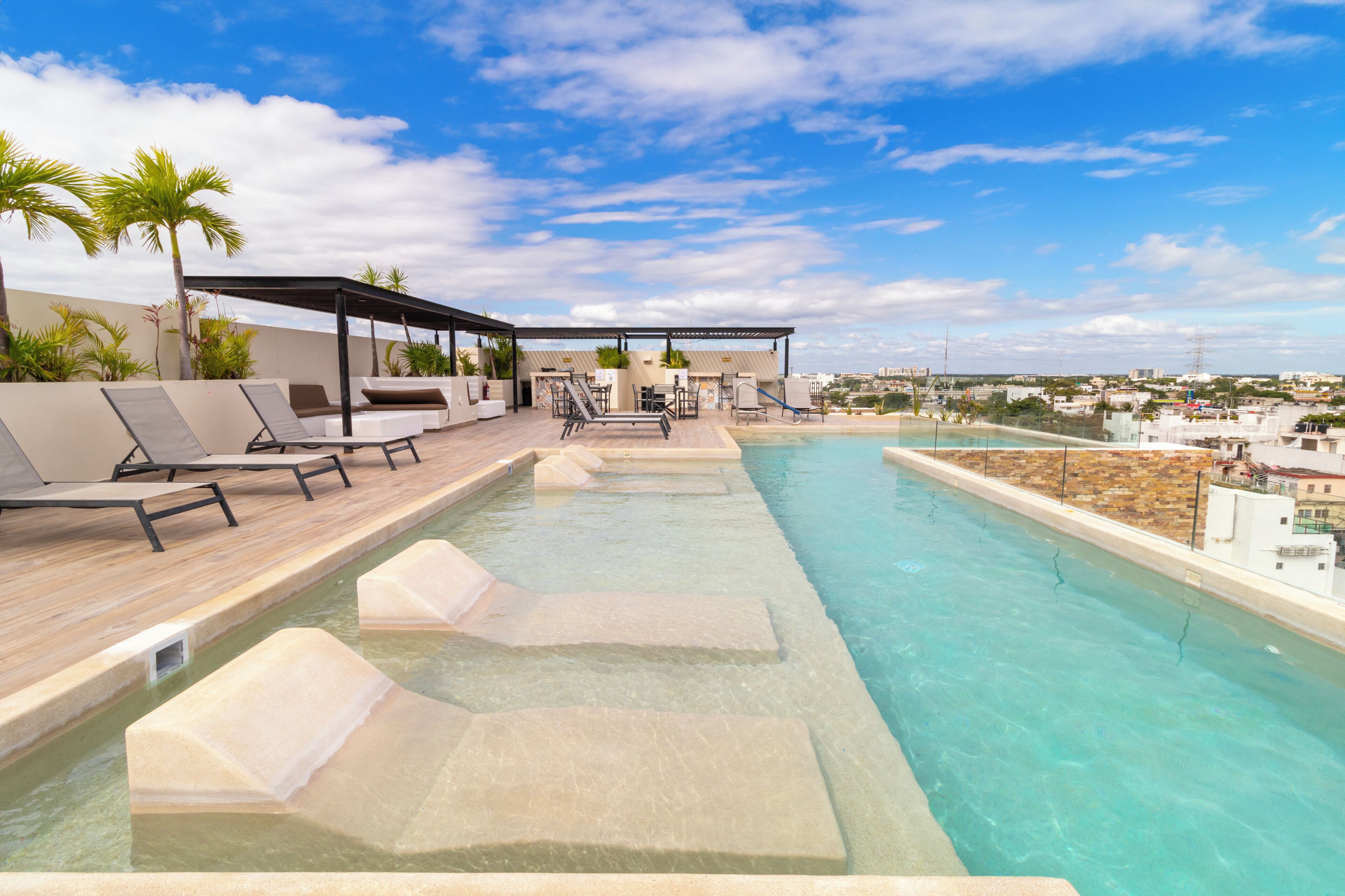 Una piscina al aire libre, sombrillas, sillones reclinables de piscina