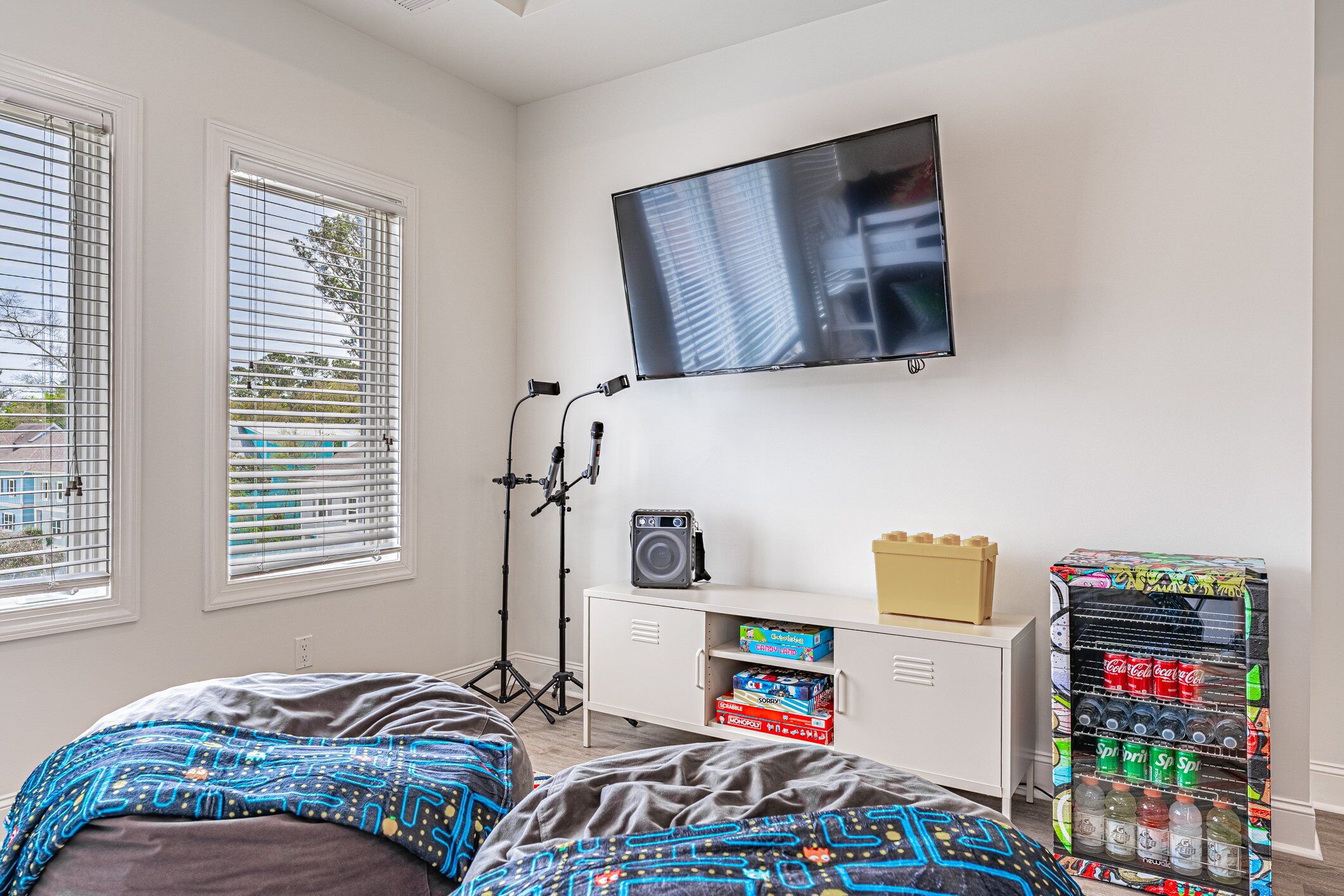 Une chambre avec deux lits, un téléviseur, un haut-parleur, un meuble de rangement et un distributeur de boissons.
