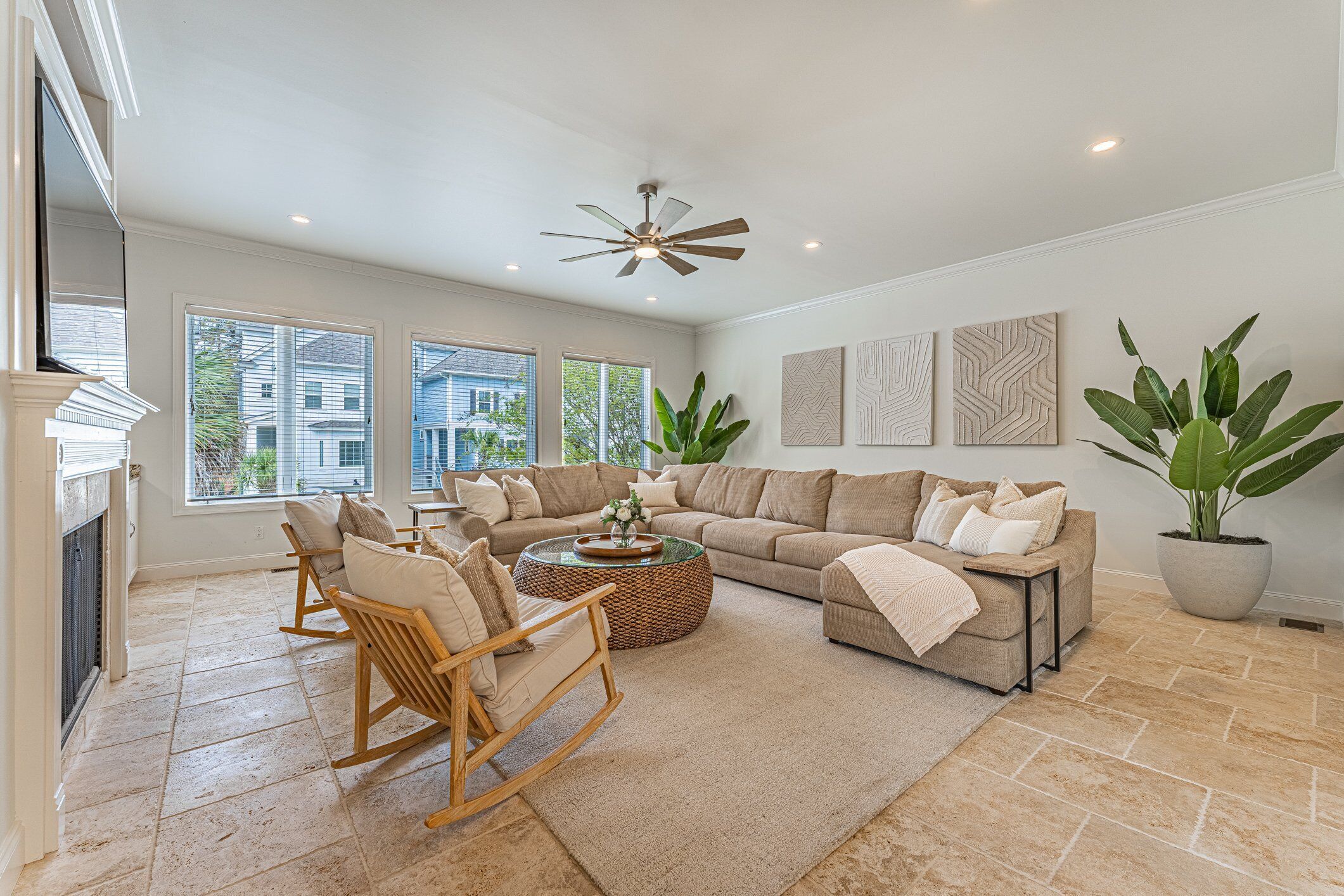 A spacious living room with a sectional sofa, a wooden rocking chair, and a large potted plant.