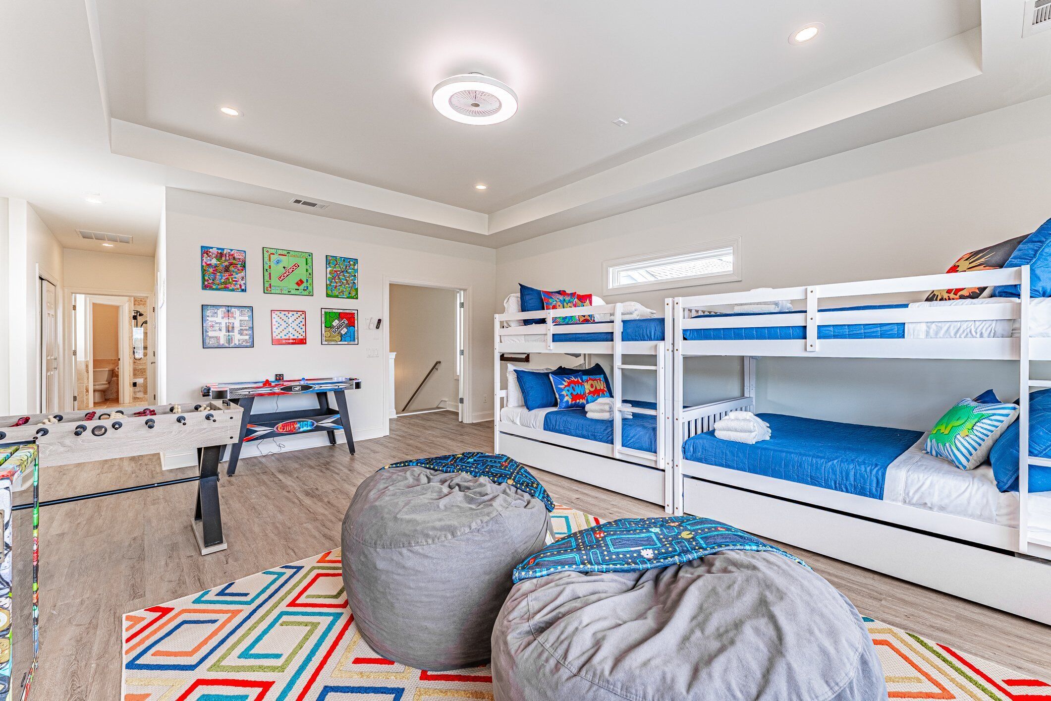 A modern, well-lit room with bunk beds, a foosball table, and bean bags.