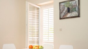 Un comedor con una mesa preparada para dos personas, un frutero y un cuadro en la pared.