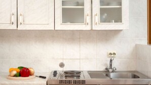 Una cocina con armarios blancos, un lavamanos de acero inoxidable y una estufa.