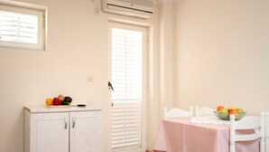 A small room with a white cabinet, a table with a pink tablecloth, and a bowl of fruit on the table. - Apartments Božica - Studio (Vrboska)