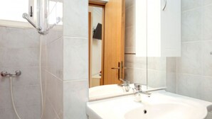 A bathroom with a shower, a sink, a mirror, and a wooden door. - Apartments Božica - Studio (Vrboska)