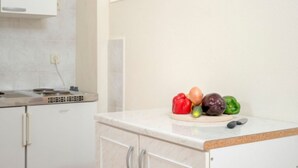 A kitchen with white cabinets, a countertop, and a window with blinds. - Apartments Božica - Studio (Vrboska)