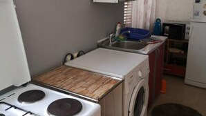 A compact kitchen with a stove, sink, and washing machine. - Apartments Roma - One Bedroom Apartment (Stanici)
