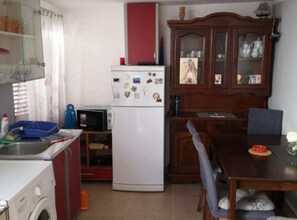 Compact kitchen with a refrigerator, microwave, and sink, perfect for meal preparation and laundry.