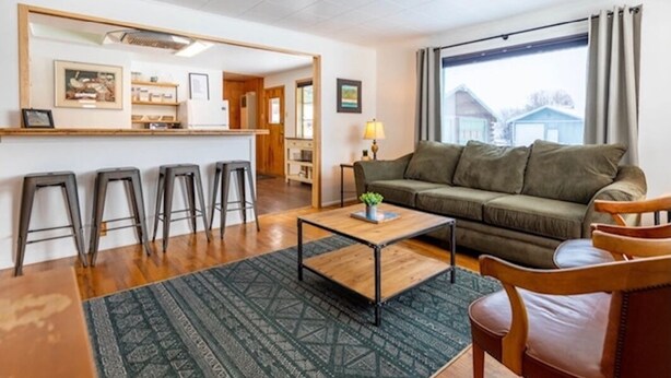 A living room with a sofa, a coffee table, and a bar area with stools.