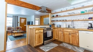 A kitchen with wooden cabinets, a built-in oven, and a dishwasher. There are shelves above the counter holding dishes and jars.