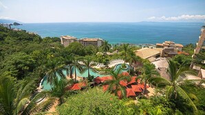 A resort with a large pool surrounded by palm trees and a view of the ocean.