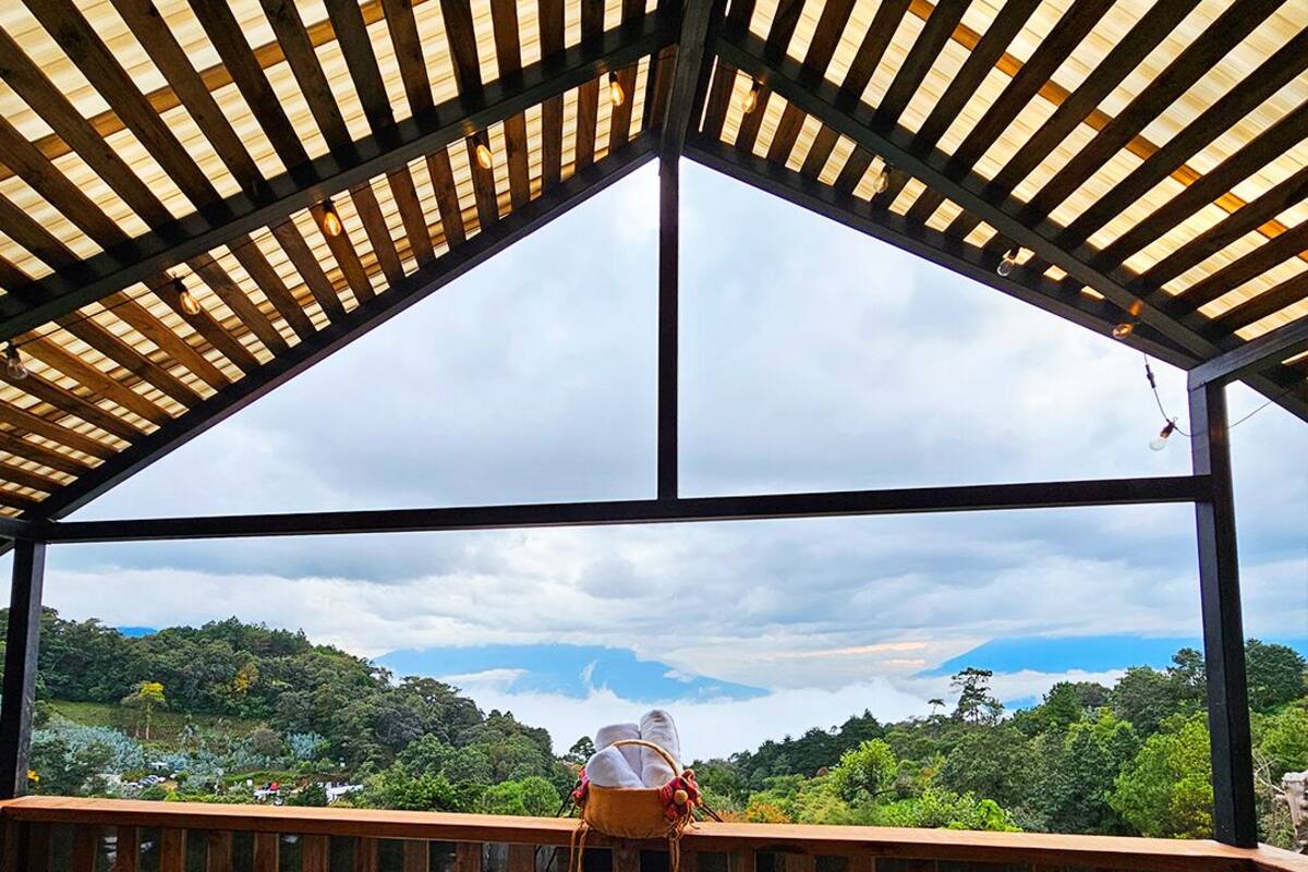 Lämminvesiallas puisen pergola-katoksen alla, josta avautuu näkymä metsäiseen maisemaan.