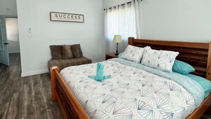 Un dormitorio con cama, ventilador de techo, equipo de aire acondicionado, letrero en la pared y una ventana con cortinas.