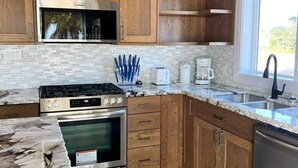 Una cocina moderna con armarios de madera, una estufa de acero inoxidable, un horno y un lavavajillas.