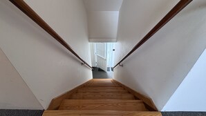 A wooden staircase with white walls and a door at the top. - Historic Island Pond Home on VAST Trail – 3BR, 2BA (Brighton)