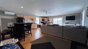 A compact living space with a kitchenette, a dining area, and a seating area with a sofa and chairs. - Island Pond Apartment on VAST Trail – 3BR, 2BA (Brighton)