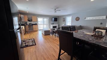 A spacious kitchen with wooden cabinets, a dining area with a marble table, and a fireplace.