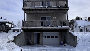 A two-story house with a balcony and a garage. - Island Pond Apartment on VAST Trail – 3BR, 2BA (Brighton)