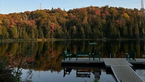 A calm lake with a dock and green benches. - Repère Öra | Spa, ski & nature (Saint-Adolphe-d'Howard)