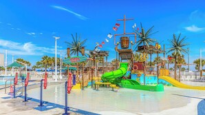 Ein Wasserpark mit einer grünen Wasserrutsche, einem Poolbereich und einer Spritzzone.