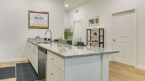 A modern kitchen with a granite countertop, built-in dishwasher, and a framed certificate on the wall. - Walkable Downtown LaBelle Apt w/ Private Balcony! (LaBelle)