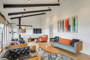 A modern living room with a fireplace, sofa, coffee table, and a colorful abstract painting. - Private Beach Access: Serene Escape in Depoe Bay (Depoe Bay)