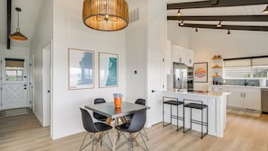 Uma cozinha moderna com armários brancos, uma ilha central e uma área de refeições com mesa e cadeiras.