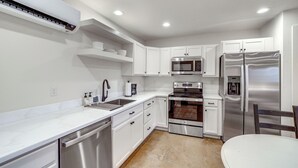 A modern kitchen with white cabinetry, stainless steel appliances, and a dishwasher. - Central & Modern Studio w/ Workspace in Owasso! (Owasso)
