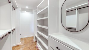 A walk-in closet with open shelving, a mirror, and a door leading to another room. - Central & Modern Studio w/ Workspace in Owasso! (Owasso)