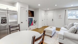 A modern kitchen with stainless steel appliances, a dining table with chairs, a sofa, and a coffee machine. - Central & Modern Studio w/ Workspace in Owasso! (Owasso)