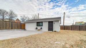 A single-story house with a front door, a small porch with two chairs, and a concrete driveway. - Central & Modern Studio w/ Workspace in Owasso! (Owasso)