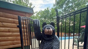 A bear statue on a platform with steps, a pool, and a wooden fence in the background.
