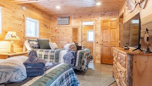 A cozy cabin room with two beds, a wooden dresser, and a mirror.