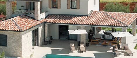 A two-story house with a swimming pool, outdoor seating area, and a vineyard in the background.