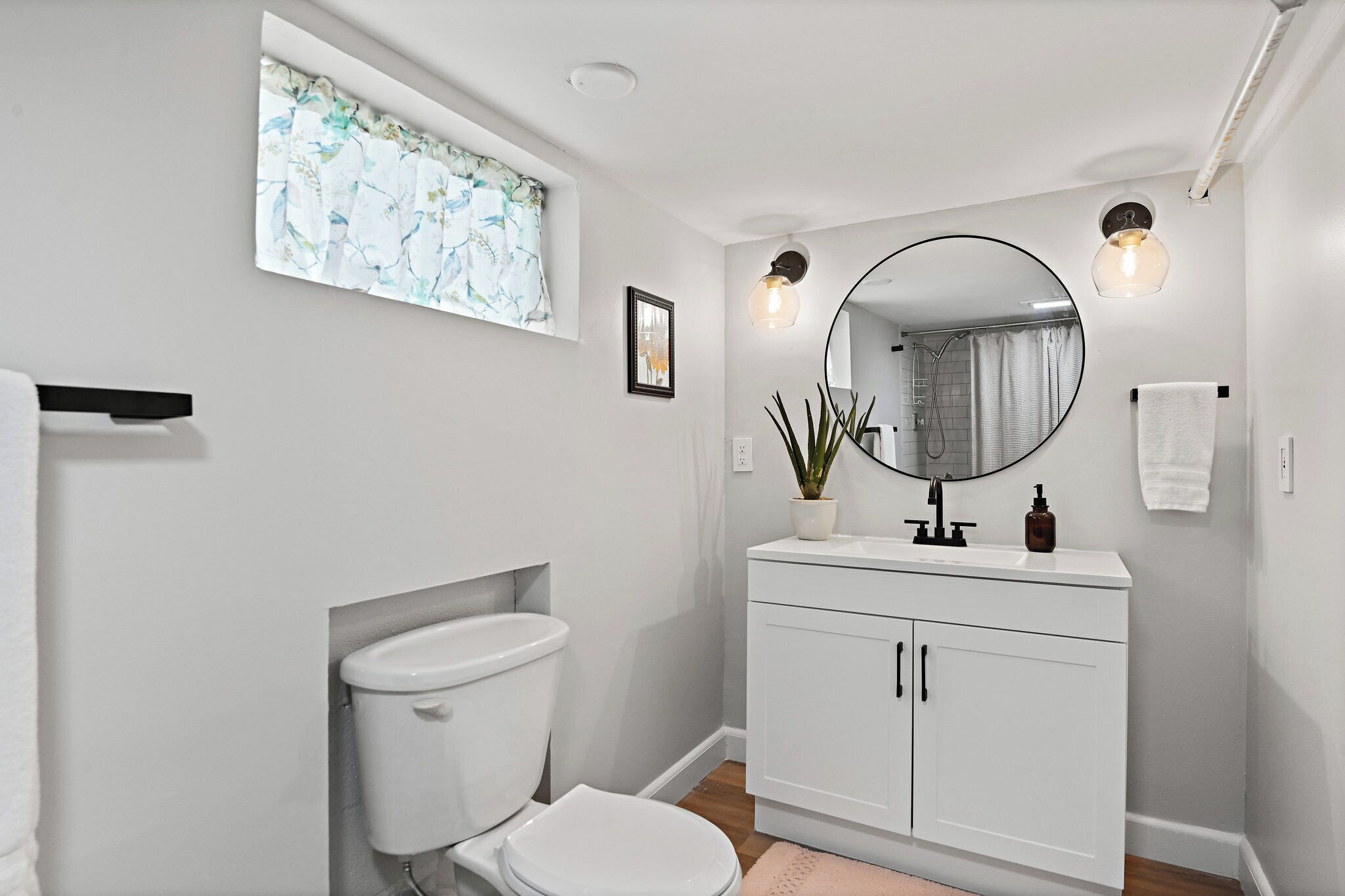 Ein modernes Badezimmer mit Toilette, Waschbecken mit Spiegel und Fenster mit Blumenmuster.