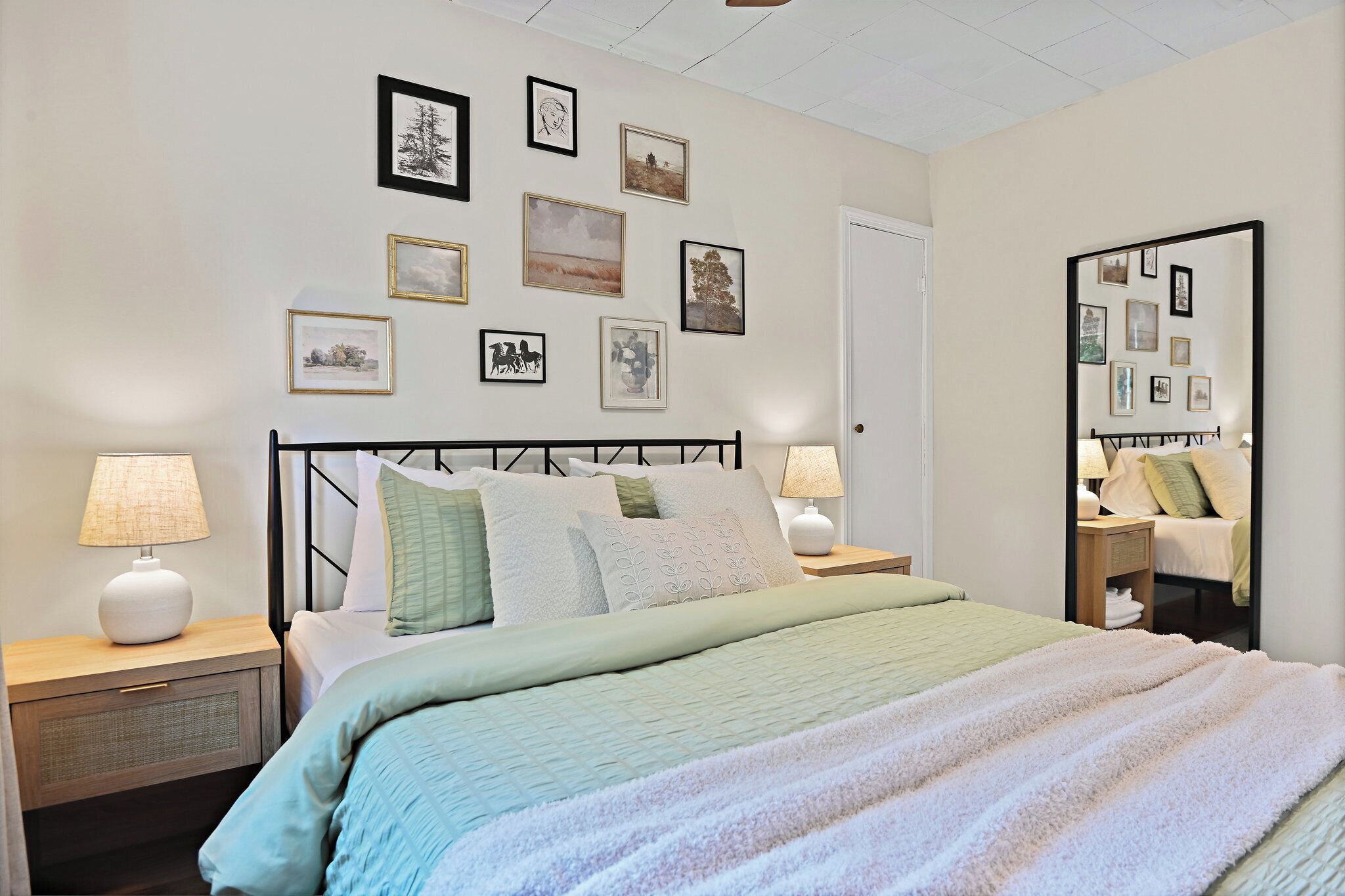 A neatly arranged bedroom with a bed, bedside tables, and a wall adorned with framed pictures.