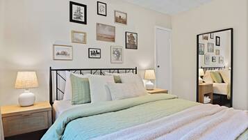 A neatly arranged bedroom with a bed, bedside tables, and a wall adorned with framed pictures.