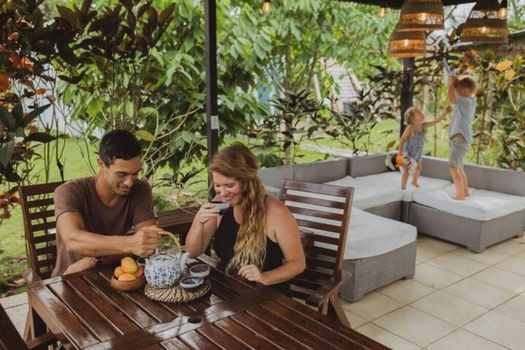 A dining area with a table set for two, surrounded by lush greenery.