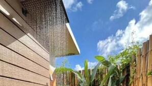 A wooden deck with a bamboo fence and lush greenery. - The Sunset Shack (Ceiba)