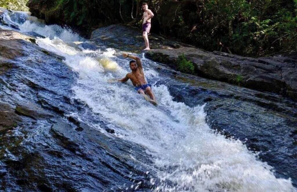 A waterfall with two individuals enjoying the water.