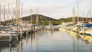 Een jachthaven met vele boten afgemeerd, omringd door heuvels.