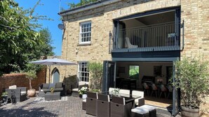 Un bâtiment en pierre de deux étages doté d’un patio aménagé avec du mobilier d’extérieur et un grand parasol.