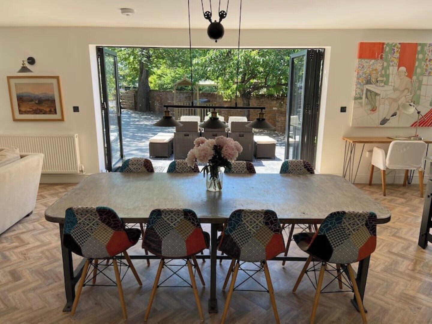 Un coin repas avec une grande table, six chaises et un vase rempli de fleurs.
