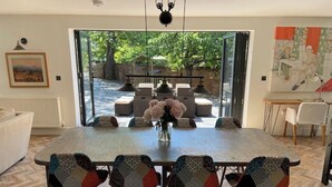 Un coin repas avec une grande table, six chaises et un vase rempli de fleurs.