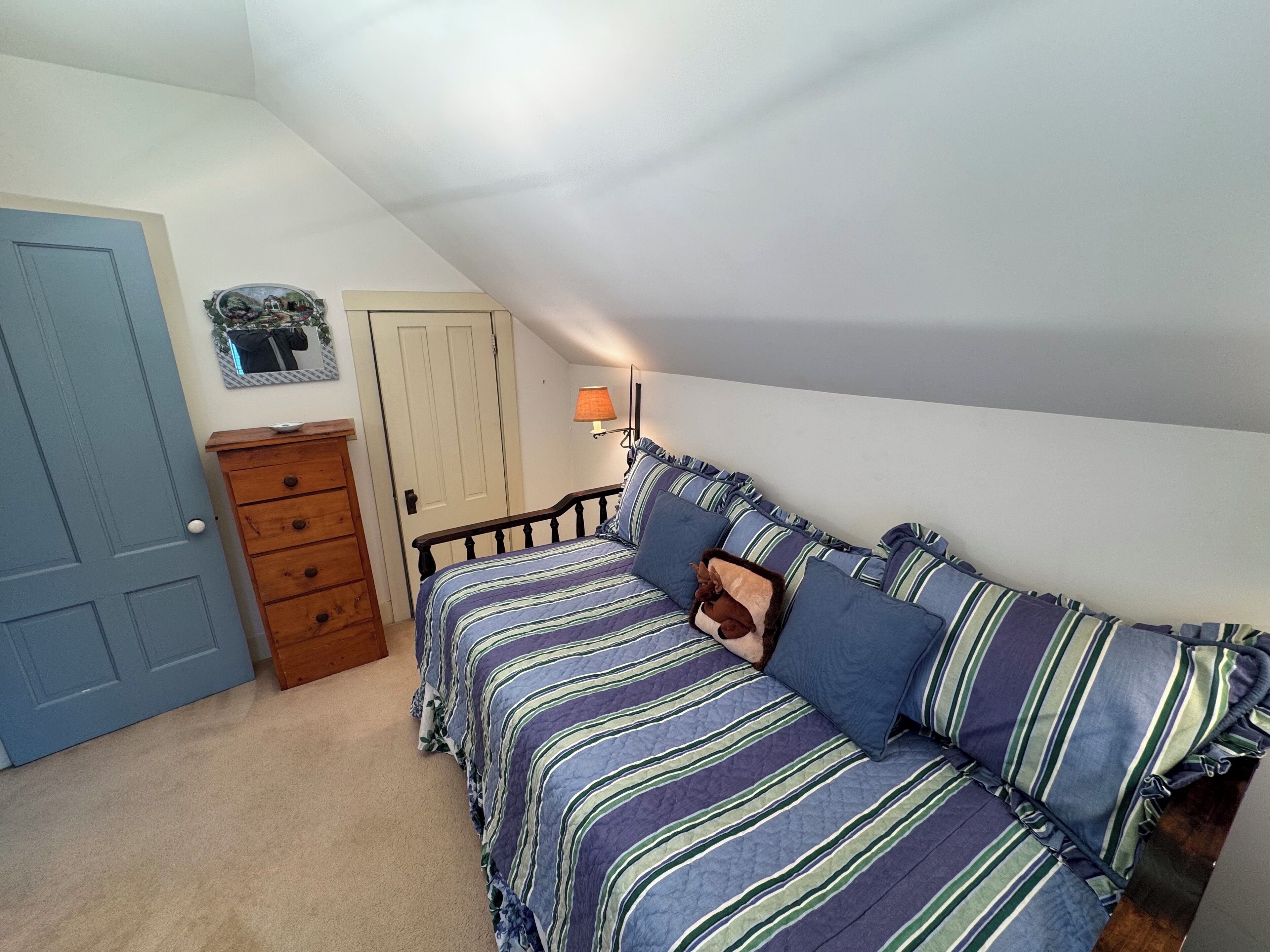 A bedroom with a bed, dresser, and a door.