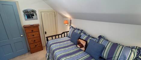 A bedroom with a bed, dresser, and a door.