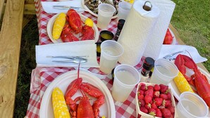 A table set with seafood, including lobsters and corn, and various condiments. - Charming Rockport, Maine 3BR – Walk to Picturesque Harbor & Downtown (Rockport)
