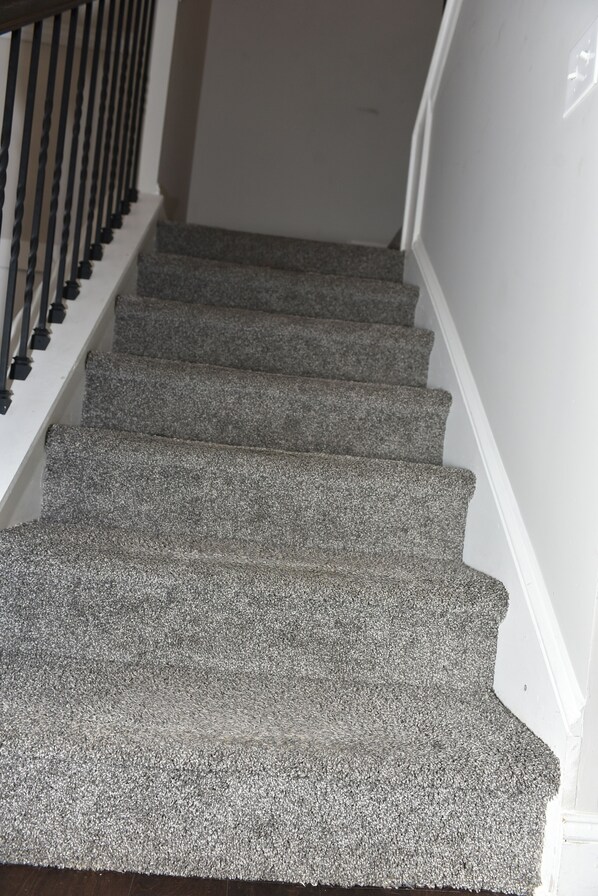 A staircase with carpeted steps and a black railing.