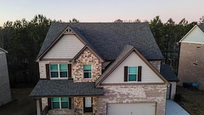 A two-story house with a garage, a stone accent wall, and a covered front porch. - Spacious 5-bedroom house with AC and WiFi in charming Lawrenceville (Lawrenceville)